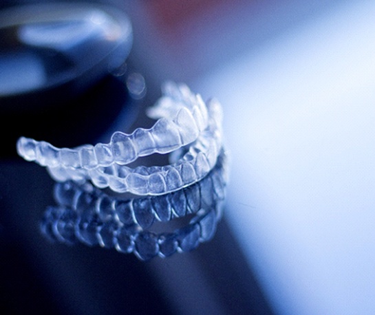 Two Nu Smile Aligners sitting on reflective surface