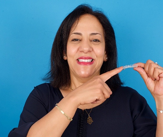 Happy middle-aged woman pointing at her clear aligner