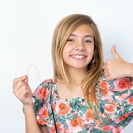 Preteen girl holding clear orthodontic aligner