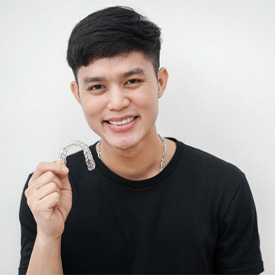 Young man holding his Invisalign in Barnegat on white background