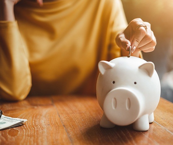 Person putting a coin in a piggy bank