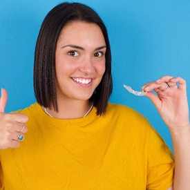 Woman in yellow shirt giving thumbs up for clear aligner treatment