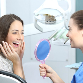 Woman admiring her smile after Invisalign in Eatontown