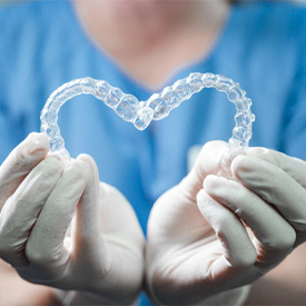 dentist holding Invisalign aligners in Eatontown in heart-shape