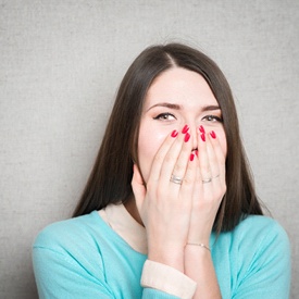 Woman covering her smile, embarrassed by gap teeth