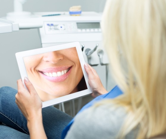 Woman looking at smile design on tablet computer