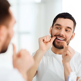 Closeup of man smiling while flossing his teeth