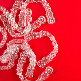 several clear aligners in front of a red background