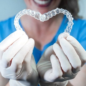 dentist holding two clear aligners in a heart shape