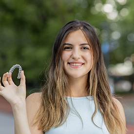 Woman smiling after paying for Invisalign aligner replacement in Staten Island 