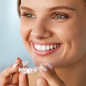 Healthy smiling woman holding Invisalign in Barnegat  