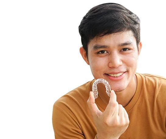 Happy teen boy holding his Nu Smile clear aligner