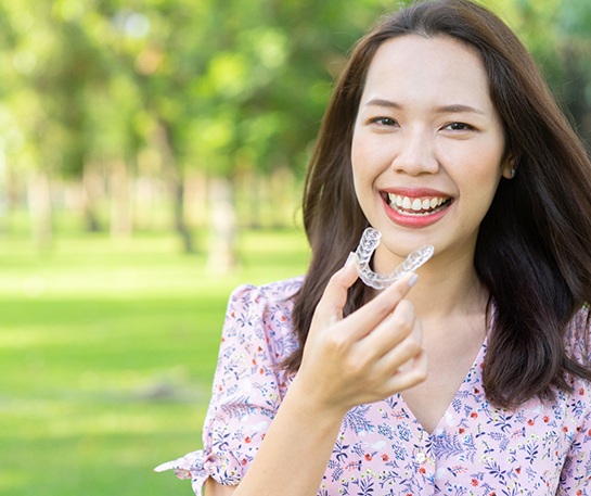 Smiling woman with Invisalign in Staten Island alternative outside