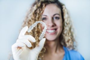 Happy dental professional holding Nu Smile Aligner in gloved hand