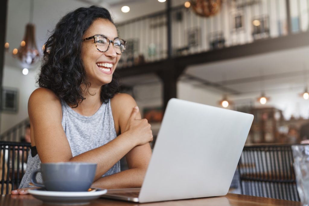 Smiling woman working on laptop in coffee shop