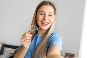 Woman in blue t-shirt holding two clear aligners