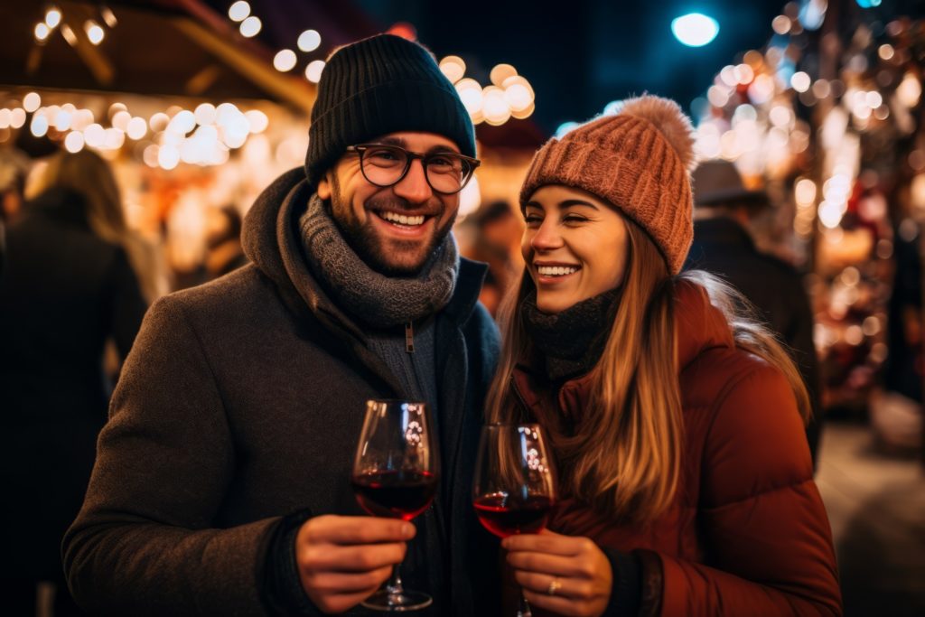 Couple smiling while enjoying glass of wine outside during the holidays