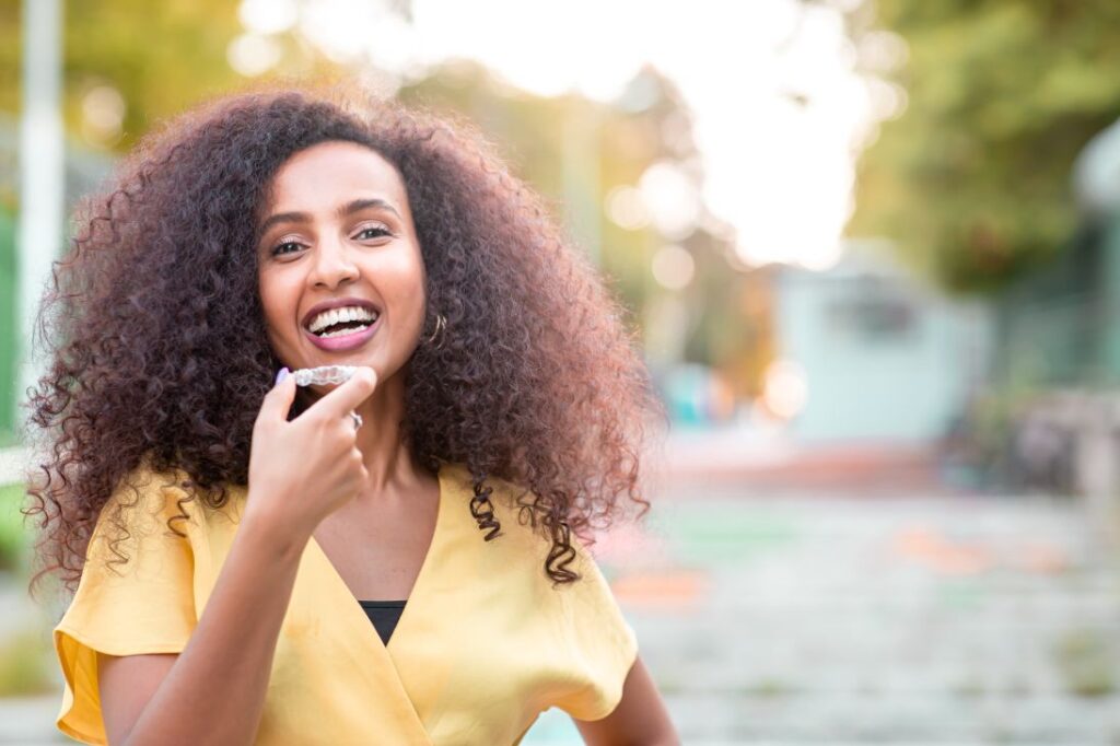 A woman holding a Nu Smile aligner